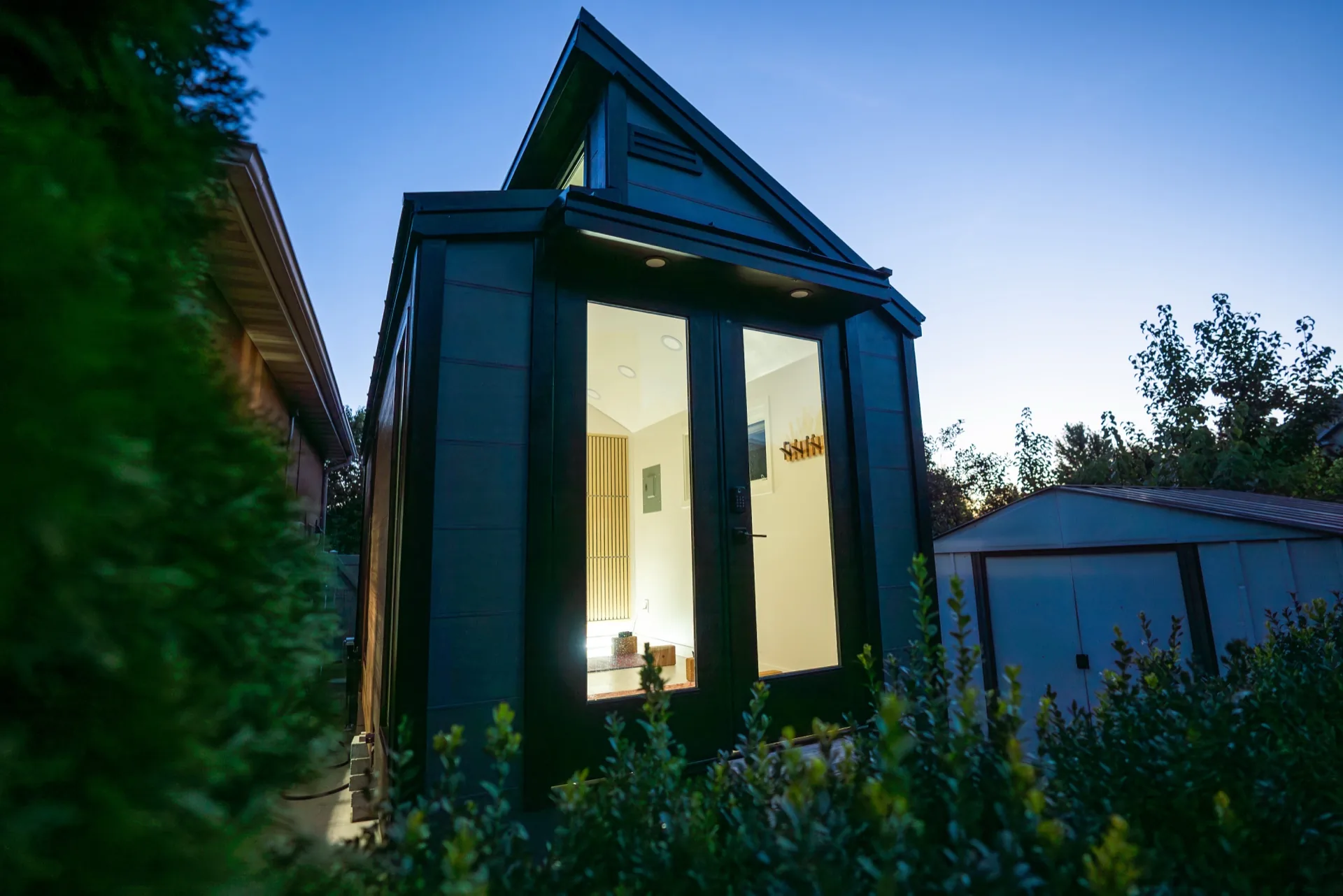 Sauna Haus exterior at twilight with warm interior glow through glass doors